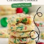 Stack of five colorful Christmas cookies with red and green sprinkles on white surface, festive ornaments behind.