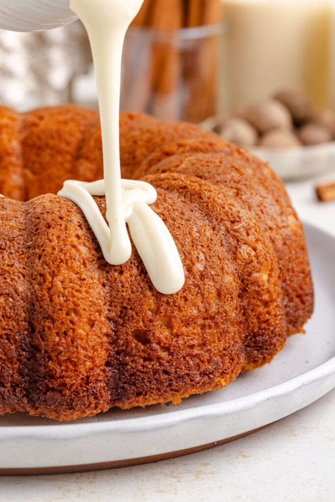 Eggnog glaze being drizzled over the bundt cake.