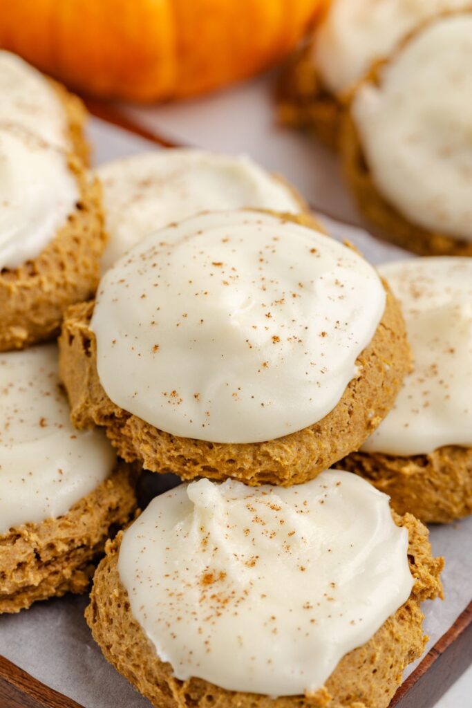 Pile of cake mix pumpkin cookies with cream cheese frosting.