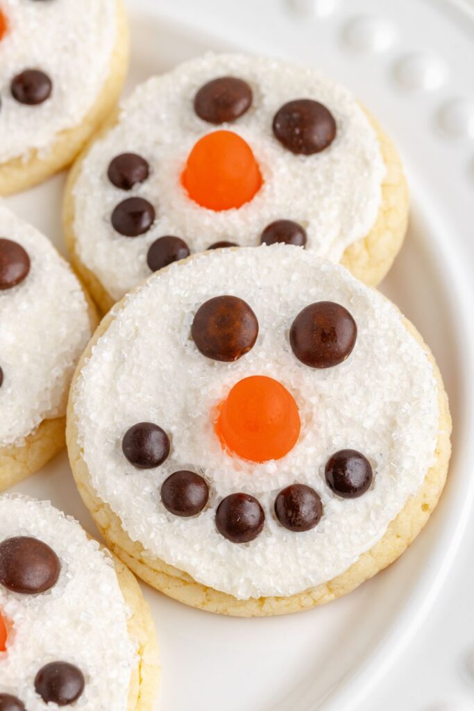 Frosted snowman face cookies on a white plate.