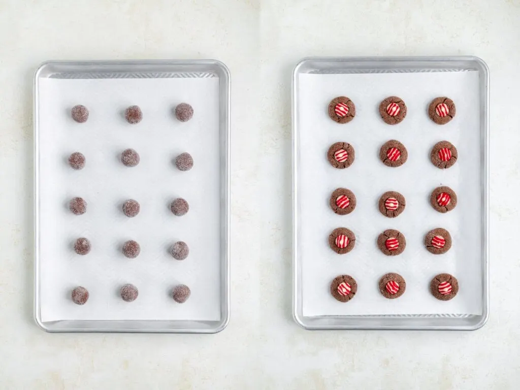 Two baking sheets lined with parchment paper. The left sheet has 16 round chocolate cookie dough balls. The right sheet shows the same cookies pressed with three red and white striped candy cane kiss candies on top of each.