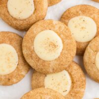 Close-up of several cinnamon cookies with creamy white centers, sprinkled with a touch of cinnamon on top, arranged on a white background.