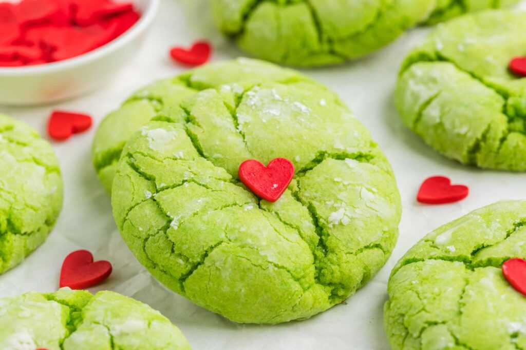 Cake mix Grinch cookies with red hearts on the counter.