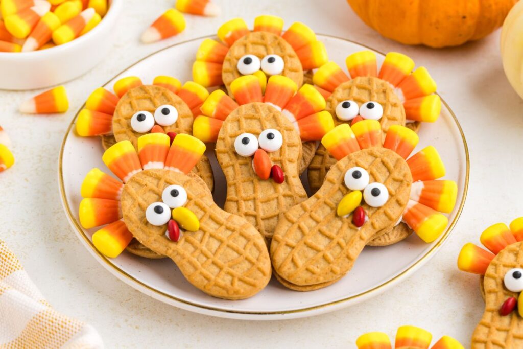 Nutter Butter cookies decorated like turkeys on a white plate with a gold rim.