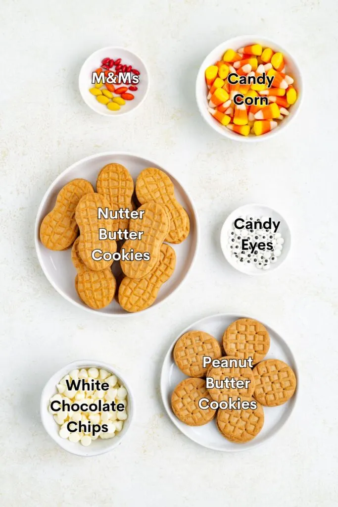 Ingredients such as Nutter Butter cookies, peanut butter cookies, white chocolate chips, candy corn, candy eyeballs, and M&Ms displayed on the counter.