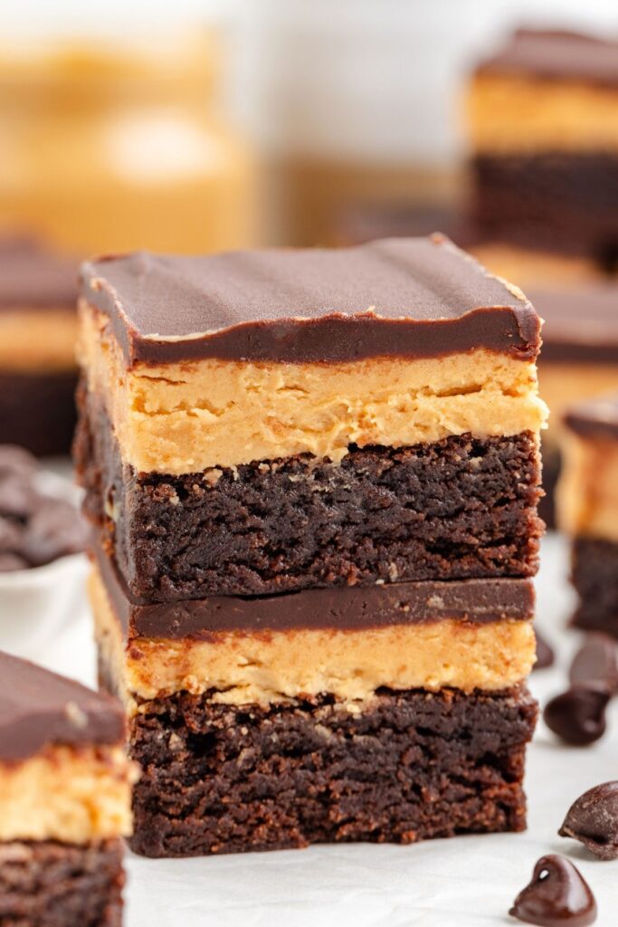 A close-up of two stacked buckeye brownies with a smooth chocolate topping.