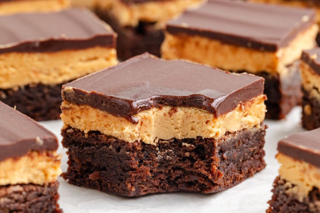 Close-up of Buckeye Brownies with a chocolate ganache topping, a creamy peanut butter layer, and a dense brownie base.