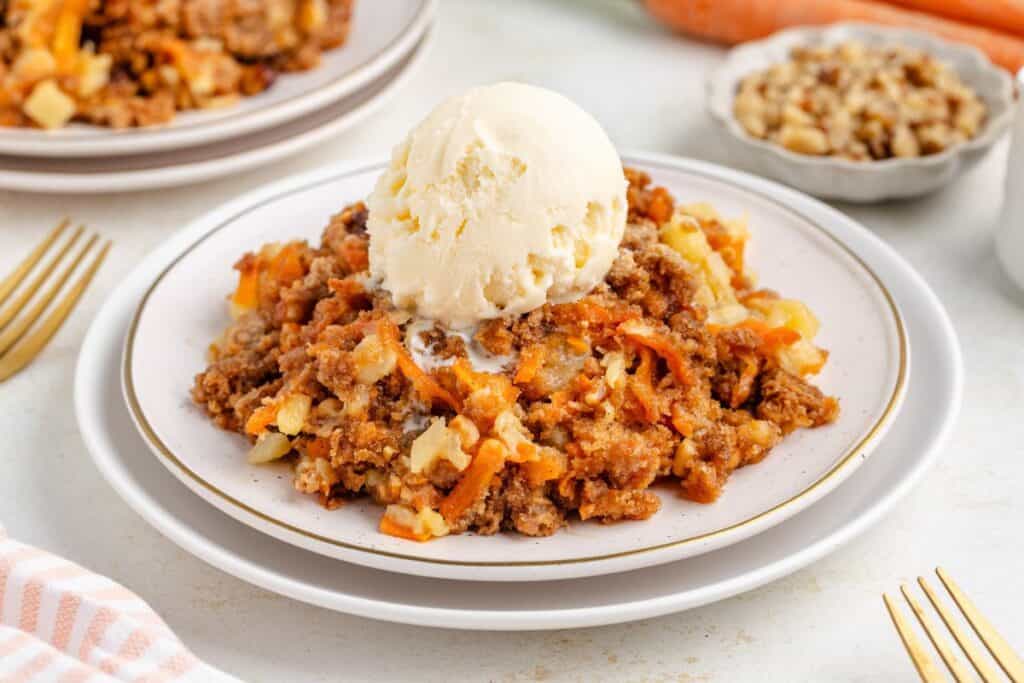 A plate of carrot cake dump cake, topped with a scoop of vanilla ice cream.