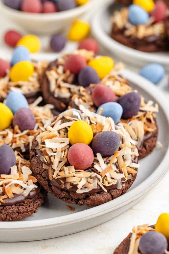 Chocolate bird nest cookies with toasted coconut hay and candy eggs on a plate.