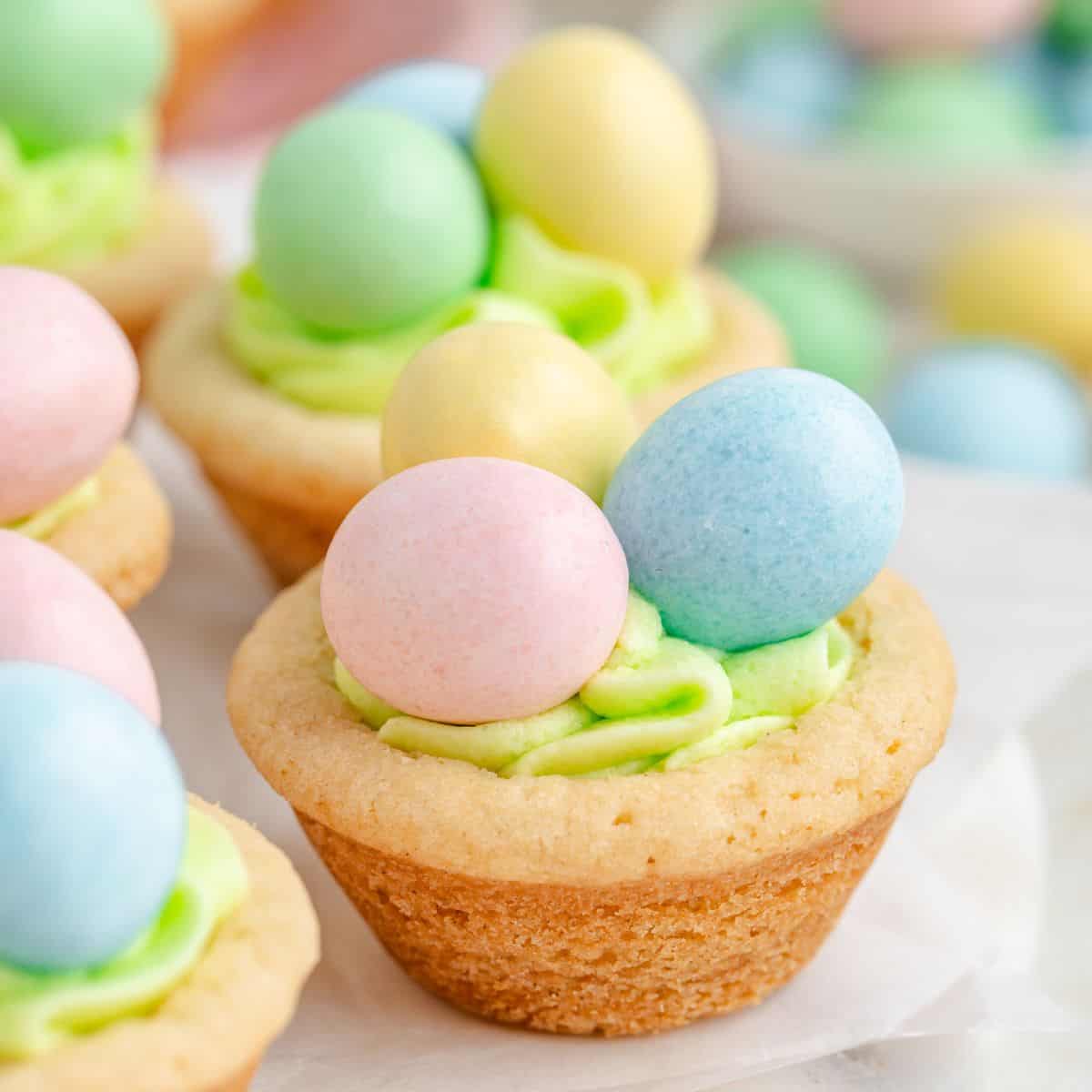 Easter cookie cups topped with green frosting and pastel-colored candy eggs.