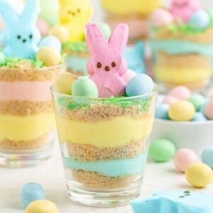 Layered Easter pudding cups with marshmallow bunnies and pastel candy eggs.