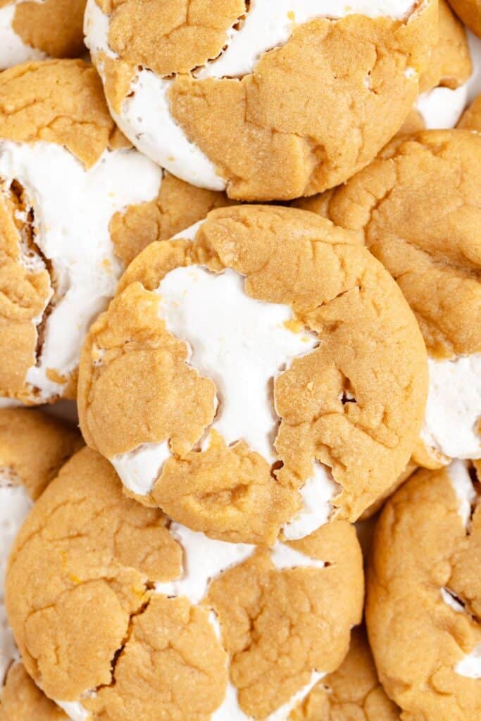 Close-up of Fluffernutter Cookies with light brown dough and white marshmallow filling, stacked together.