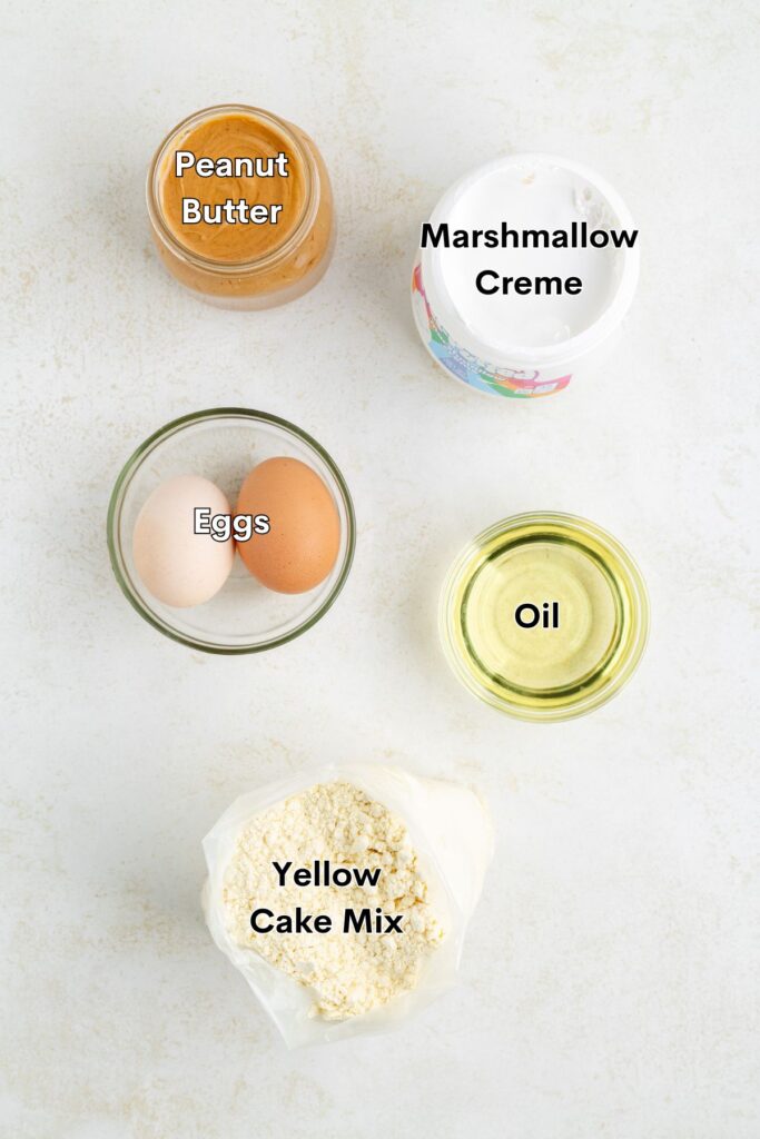 Ingredients for cookies: peanut butter, marshmallow creme, eggs, oil, and yellow cake mix on countertop.
