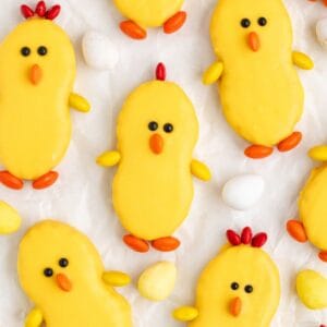 Nutter Butter chick cookies with candy accents, surrounded by speckled candy eggs on a white background.