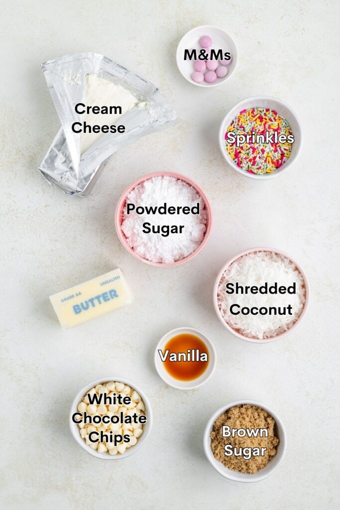 Ingredients for a dessert recipe: cream cheese, powdered sugar, butter, vanilla, coconut, brown sugar, sprinkles, M&Ms.