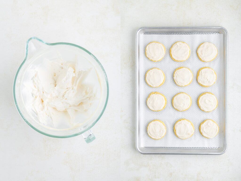 A glass bowl of white frosting next to a baking sheet with twelve frosted cookies on parchment paper.