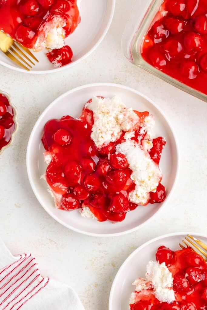 White bowls of Cherry Cream Cheese Dessert served with forks on a light background.