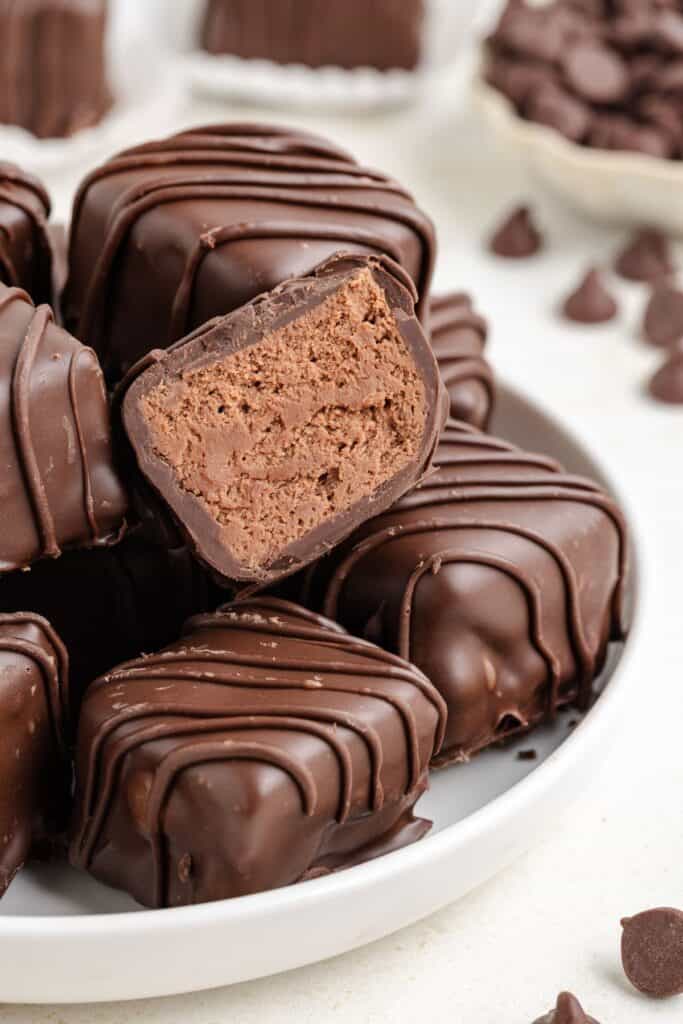 Plate of chocolate Cool Whip candy, one cut open revealing dense filling, with scattered chocolate chips in the background.