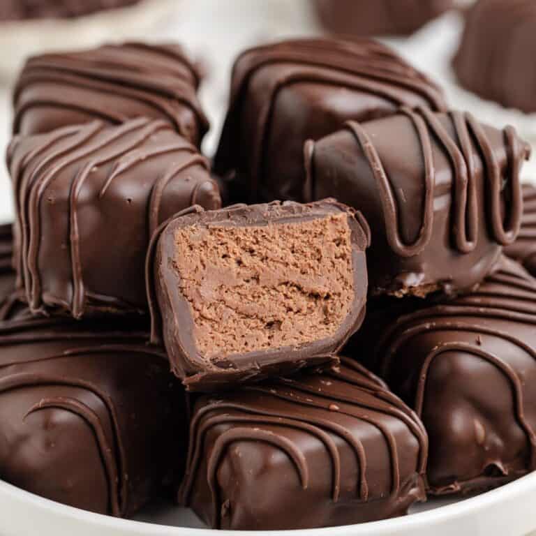 Close-up of chocolate-covered Cool Whip candy, one cut in half revealing dense, smooth filling inside.