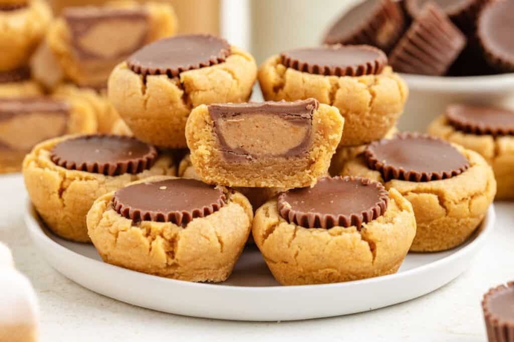 Plate of peanut butter cup cookies, one split to reveal chocolate and peanut butter filling inside.