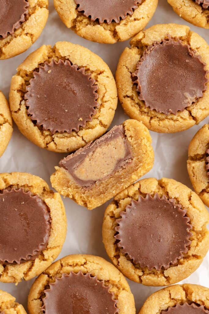 Peanut butter cookies with peanut butter cups, one sliced to reveal the inside.