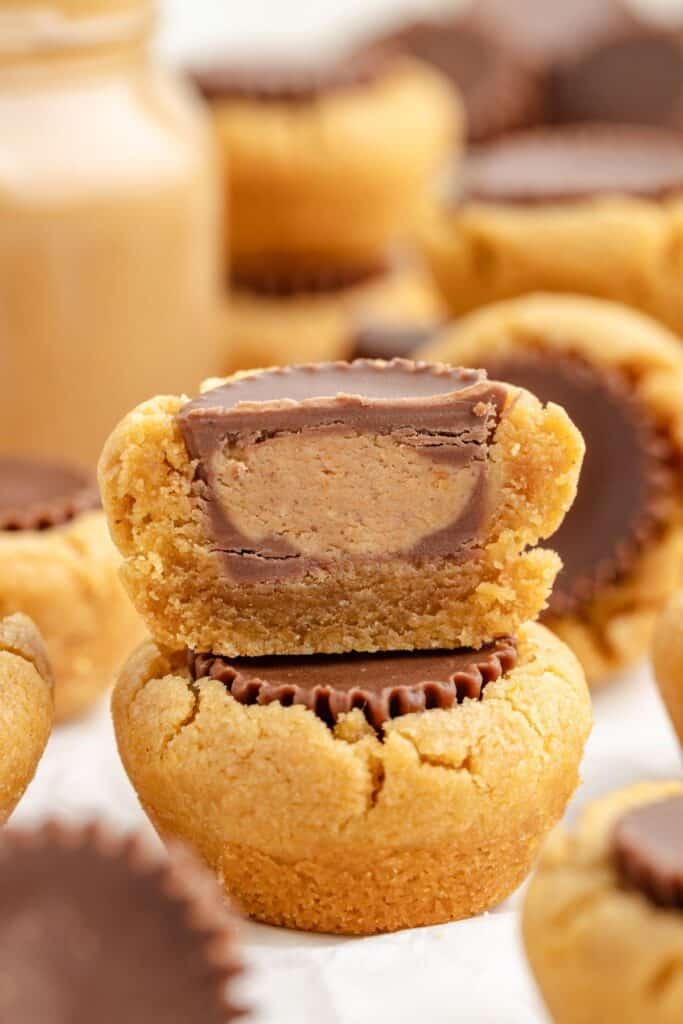 Close-up of peanut butter cookie cups with Reese's cups centers, one cut open to reveal the filling.