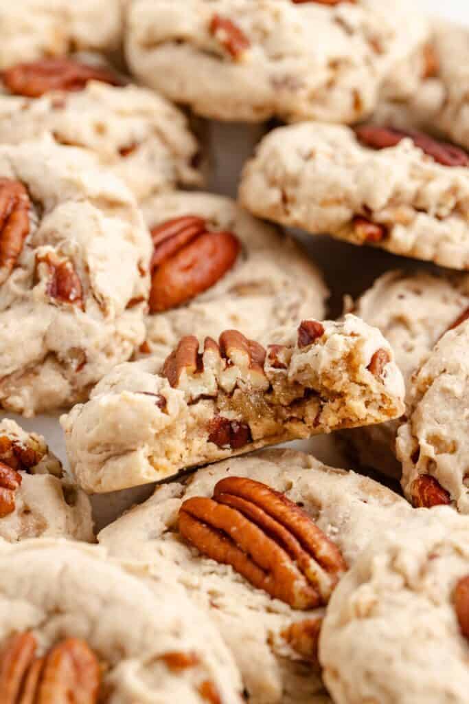 Close-up of pecan cookies, with one broken in half to reveal the inside and pecan pieces.