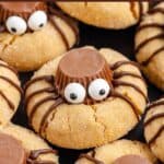 Spider Peanut Butter Cookies with chocolate, candy eyes, drizzle on top; close-up shot on a dark background.