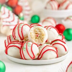 Little Debbie Christmas Tree Cake truffles with red drizzle, green sprinkles, and a bitten one showing a sprinkle-filled center.