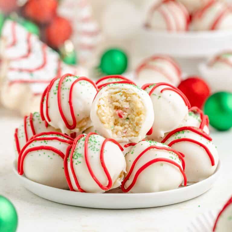 Little Debbie Christmas Tree Cake truffles with red drizzle, green sprinkles, and a bitten one showing a sprinkle-filled center.