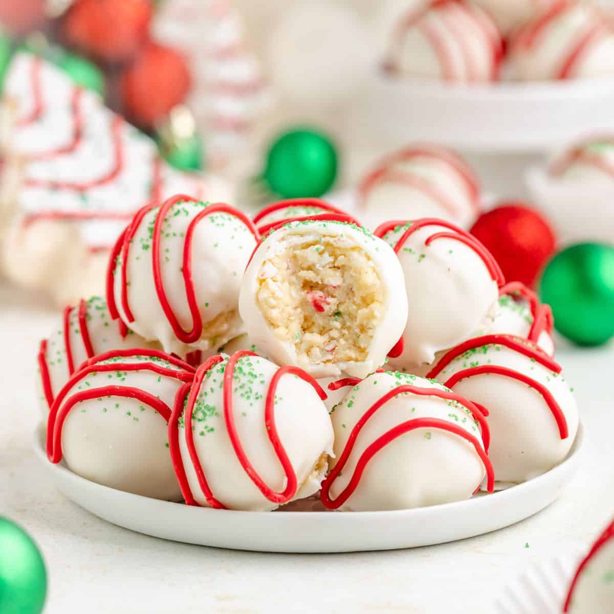 Little Debbie Christmas Tree Cake truffles with red drizzle, green sprinkles, and a bitten one showing a sprinkle-filled center.