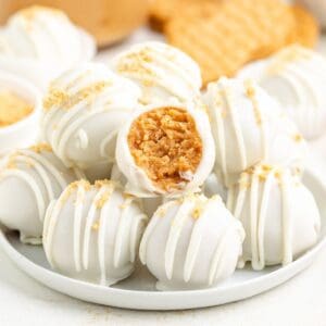 Nutter Butter Balls with cookie crumb topping on a plate, one bitten to show peanut butter filling.