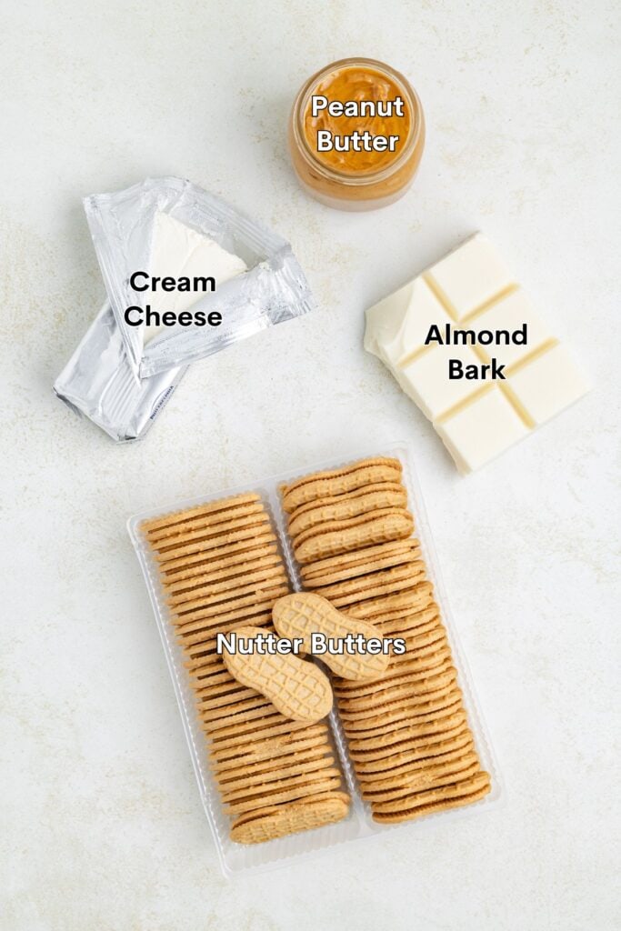 Cream cheese, peanut butter, almond bark blocks, and Nutter Butter cookies arranged on a light surface.