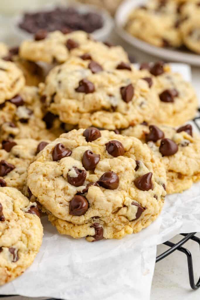 Close-up of several oatmeal chocolate chip cookies on parchment paper, with more cookies in the background.