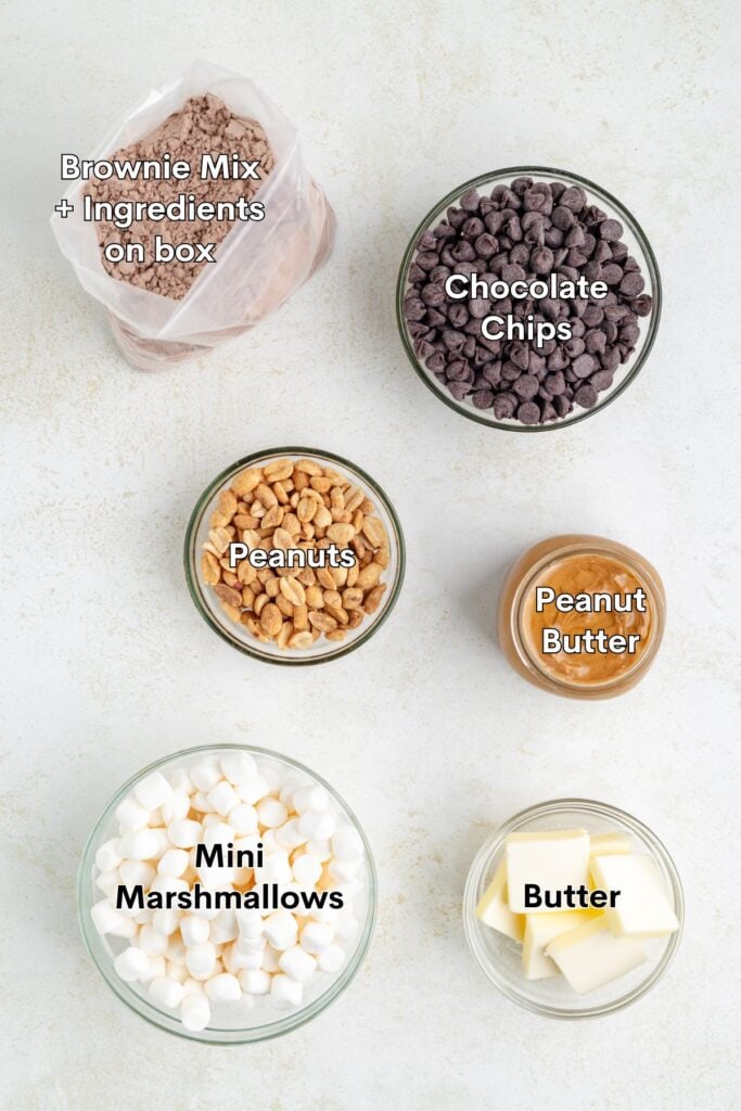 Five bowls with brownie mix, chocolate chips, peanuts, peanut butter, marshmallows, and butter, all labeled with text.