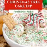 Bowl of festive Christmas Tree Cake Dip with sprinkles, surrounded by graham crackers and cookies.