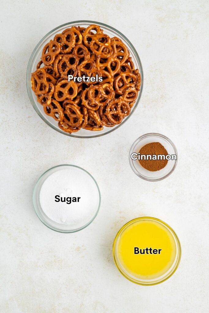 Four glass bowls with pretzels, sugar, cinnamon, and melted butter on a light surface, each labeled by ingredient.