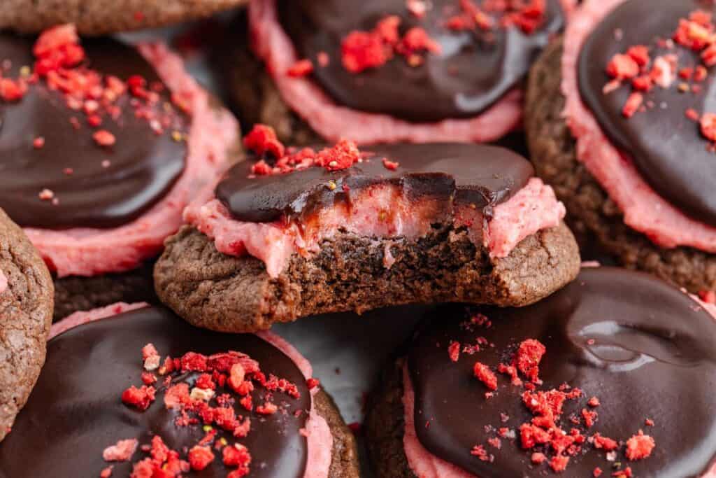 Chocolate covered strawberry cookies ; one has a bite missing.