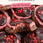 Close-up of chocolate cookies with pink strawberry frosting, chocolate glaze, red sprinkles; one has a bite taken out.