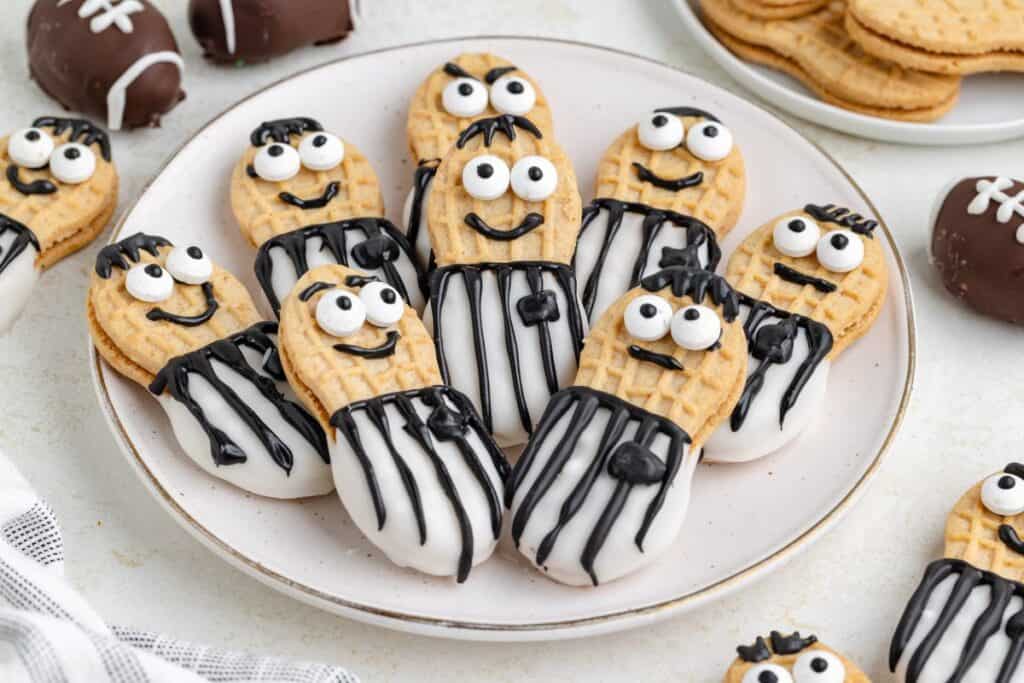 Nutter Butter referee cookies on a plate, decorated with icing and candy eyes to resemble referees.