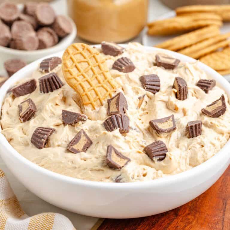 White bowl of creamy peanut butter fluff topped with chopped peanut butter cups and a Nutter Butter cookie.