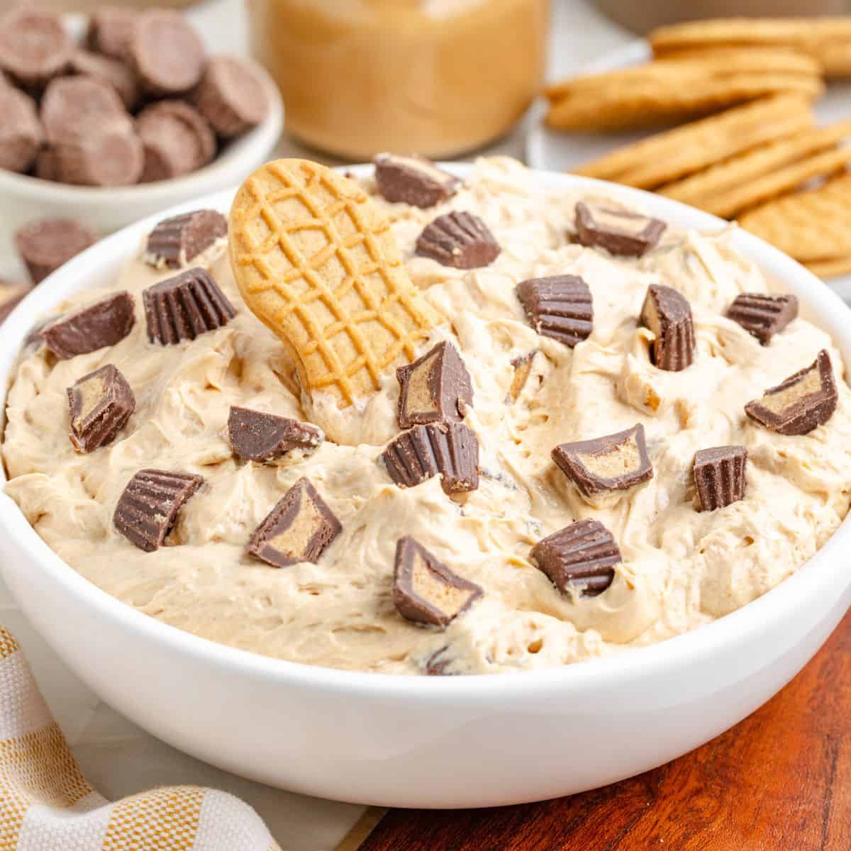 White bowl of creamy peanut butter fluff topped with chopped peanut butter cups and a Nutter Butter cookie.