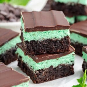 Stacked mint chocolate brownies with brownie base, green mint cream middle, and chocolate ganache top layer.