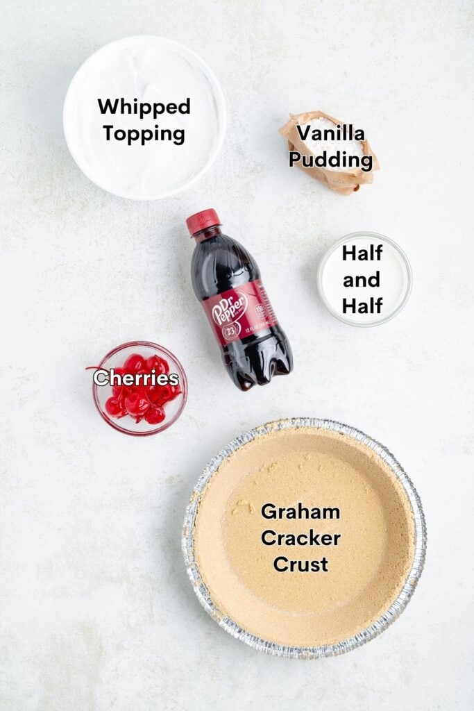 Top-down view of labeled dessert ingredients: whipped topping, pudding, half and half, Dr Pepper, cherries, graham crust.