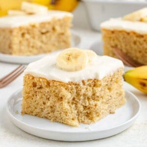 Cake mix banana cake with cream cheese frosting and banana slices, on a white plate.