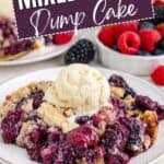 Berry Dump Cake topped with vanilla ice cream on a plate, surrounded by fresh berries and dessert in the background.