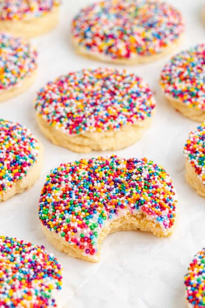 Dot Cake Cookies on parchment paper; one cookie in front has a bite missing.