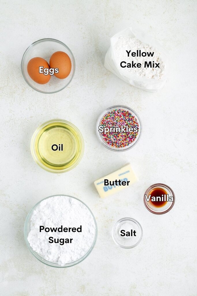Top-down view of labeled baking ingredients, including eggs, cake mix, oil, butter, sprinkles, and vanilla.
