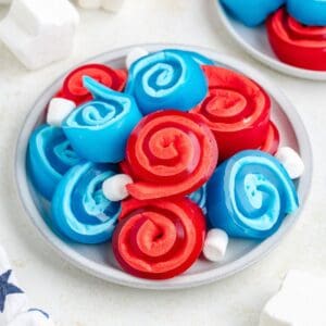 Plate with red and blue jello roll ups and some small white marshmallows.