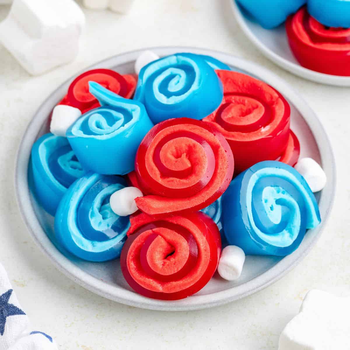 Plate with red and blue jello roll ups and some small white marshmallows.